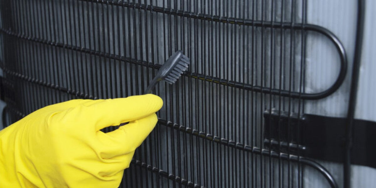 Technician cleaning commercial refrigerator condenser coils during routine maintenance