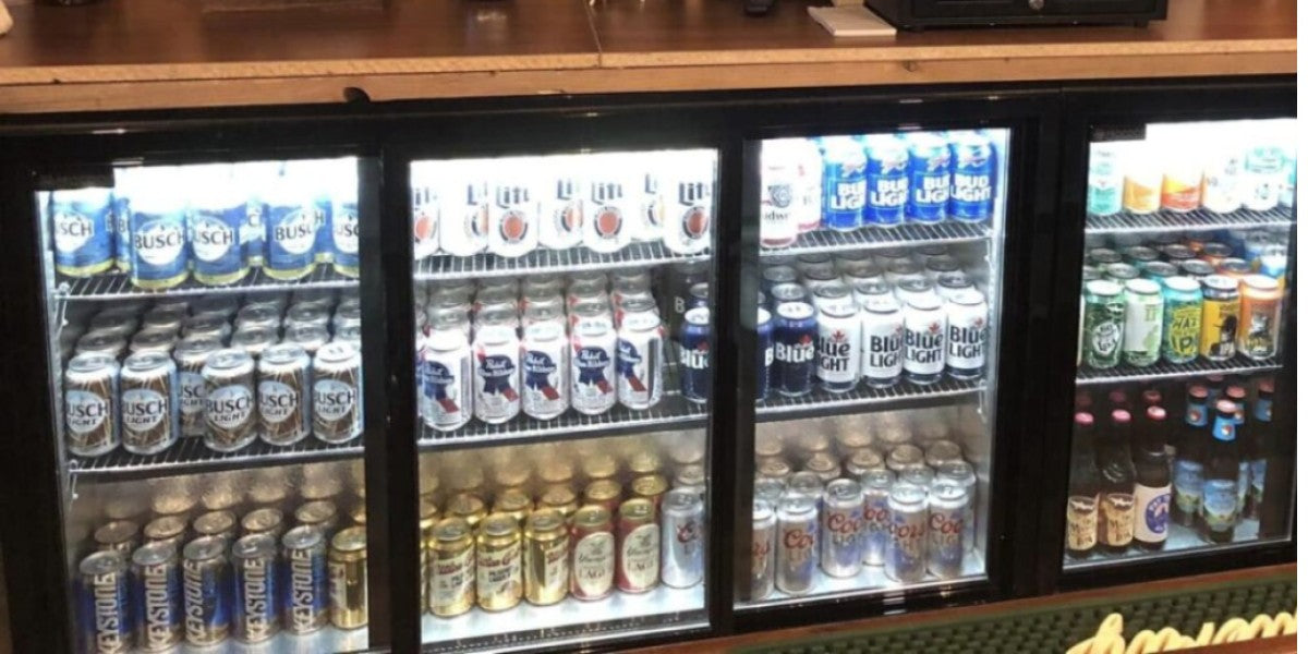 Back bar beer cooler stocked with bottles and cans at ideal serving temperature