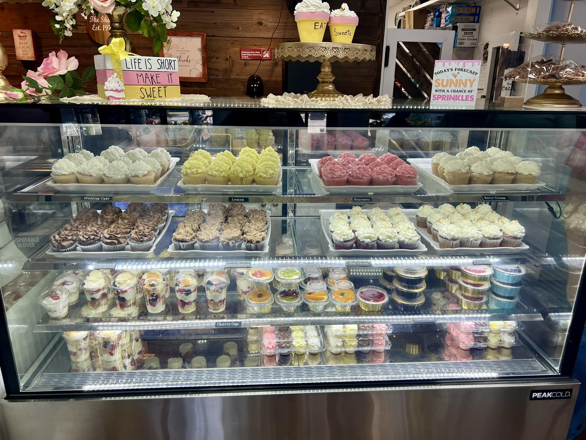 Display case with various types of cupcakes and pastries in a bakery.