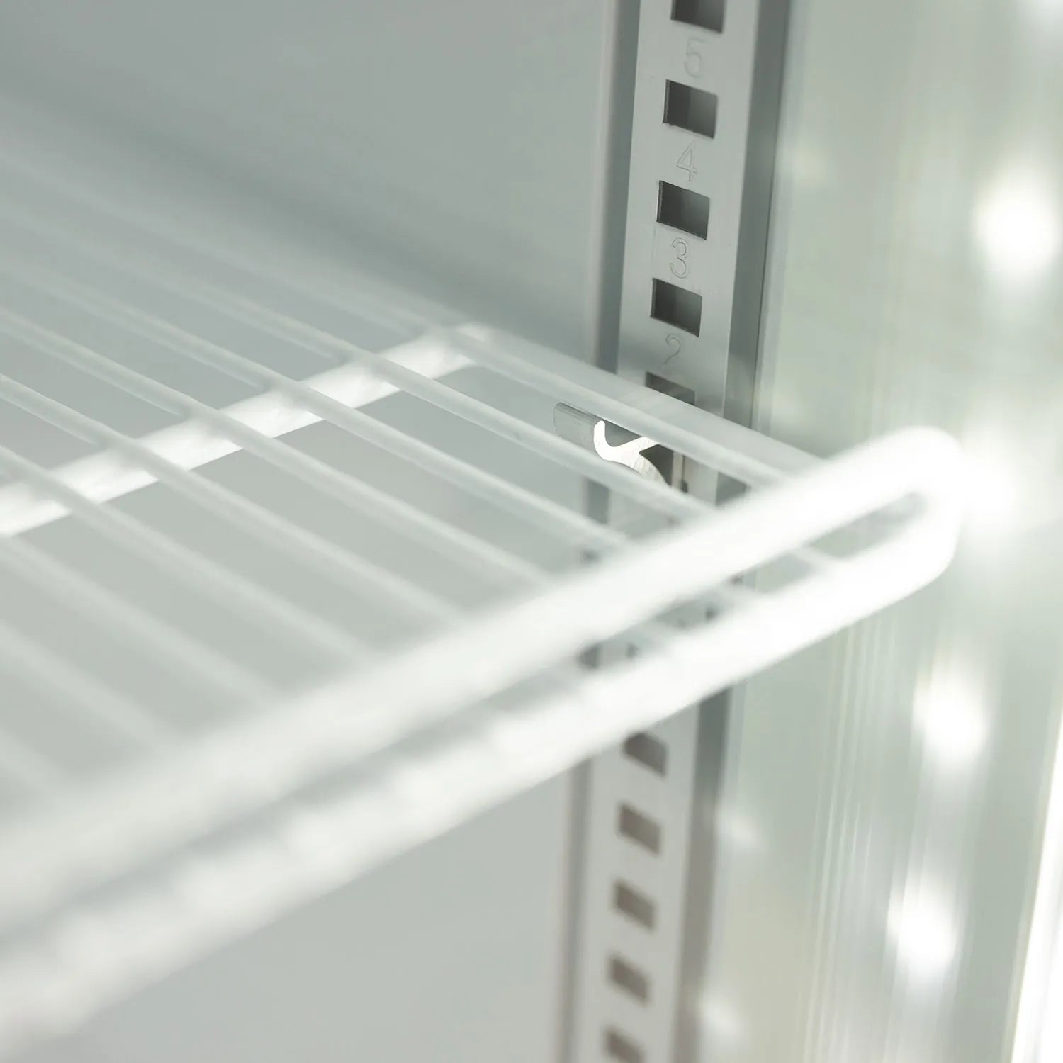 Close-up of a white metal shelf inside a refrigerator.