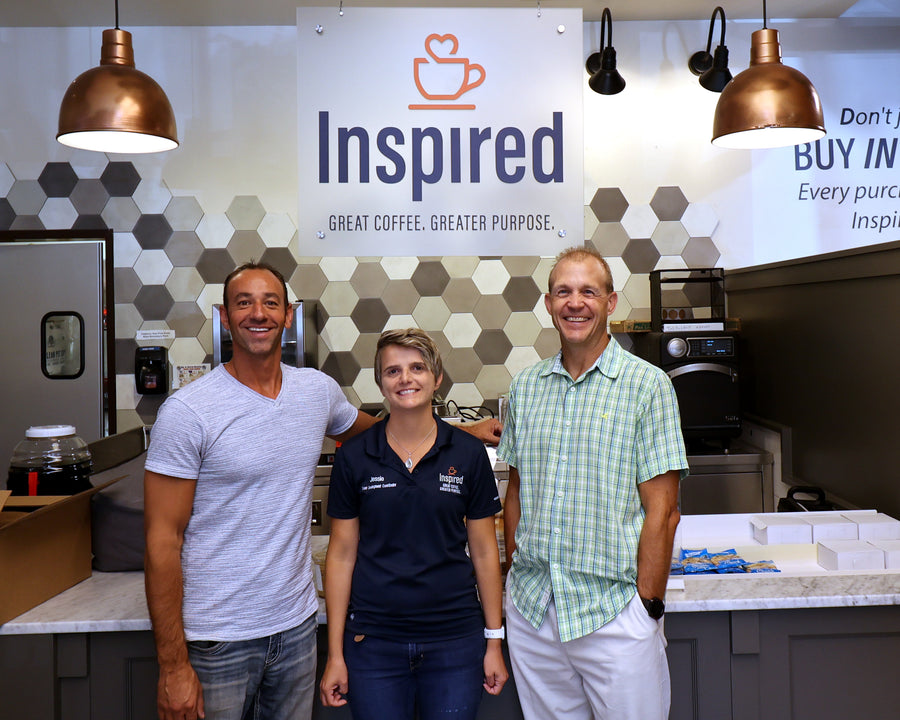 Three people standing in a coffee shop with 'Inspired' branding in the background.