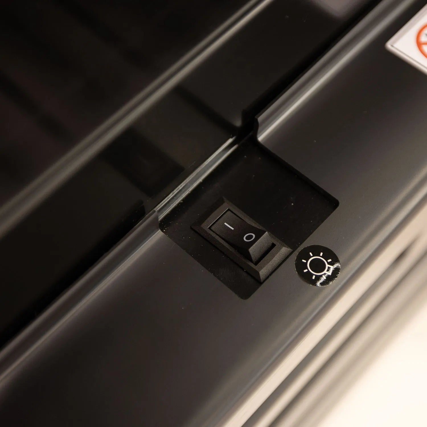 Close-up of a black switch and light bulb icon on a metallic surface