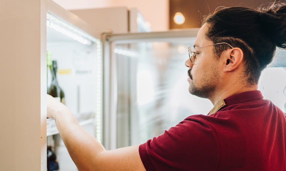 Stainless steel vs glass door freezers, man selecting a chilled bottle of wine