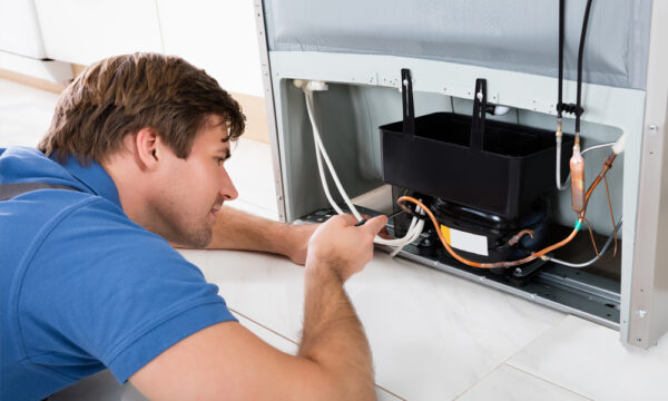 Repair person fixes commercial refrigerator, demonstrating importance of warranties