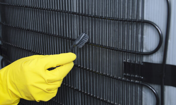 refrigerator maintenance tips, gloved hand cleaning coils