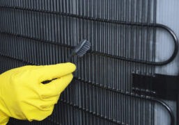 refrigerator maintenance tips, gloved hand cleaning coils